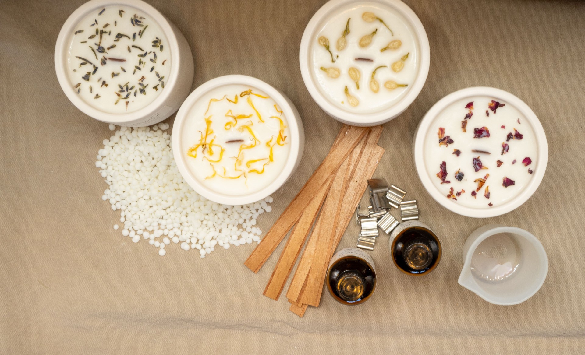 Candle maker preparing scented candles with essential oils and dried flowers